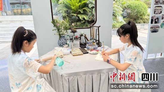 郭鑫愉(右)正在進(jìn)行花鳥畫創(chuàng)作。劉倩 攝
